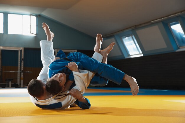 deux-jeunes-combattants-judo-kimono-s-entrainant-aux-arts-martiaux-dans-salle-sport-expression-action-mouvement_155003-32867 coach sport avec élève running